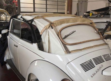 Un'auto bianca con il tetto alzato è parcheggiata in un garage.