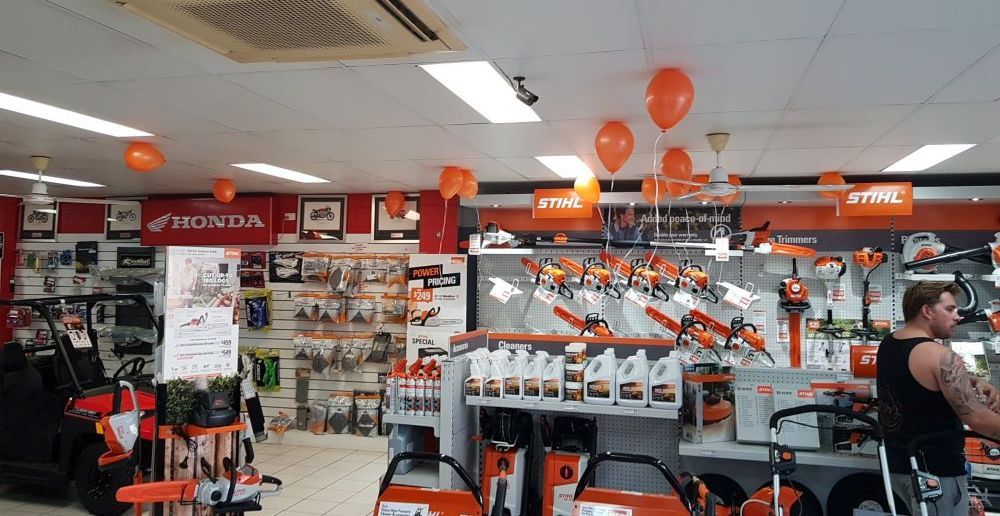 A Man is Standing in a Stihl Store With Balloons Hanging From the Ceiling — R & M Motorcycles in Katherine, NT
