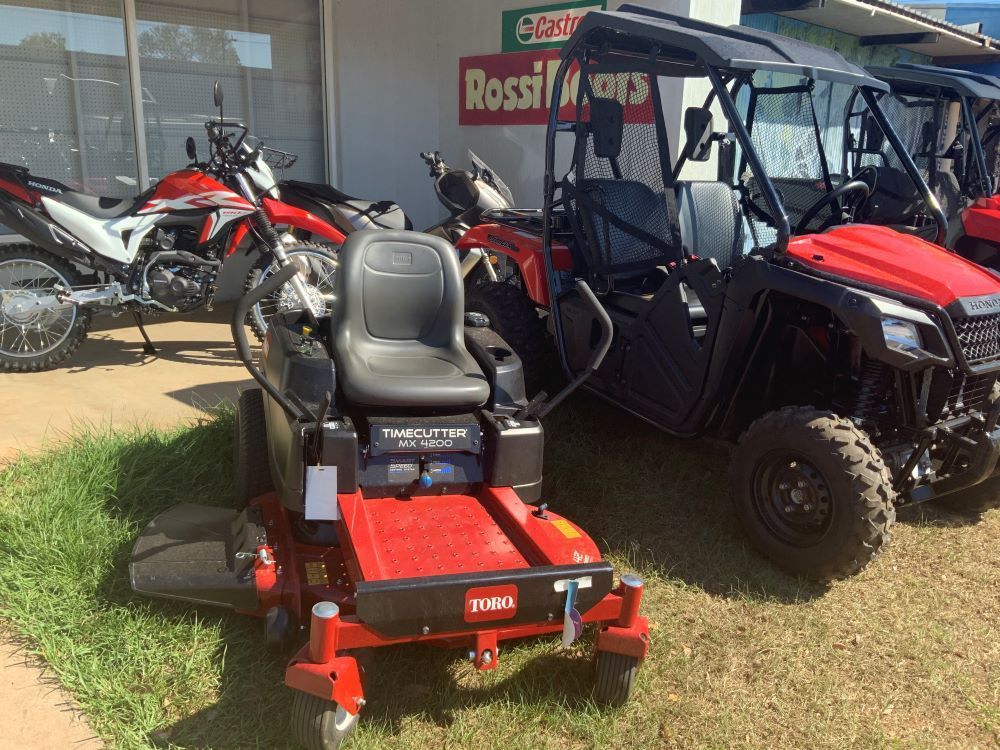 A Red Toro Lawn Mower is Parked in Front of a Row of Motorcycles and ATVs — R & M Motorcycles in Katherine, NT