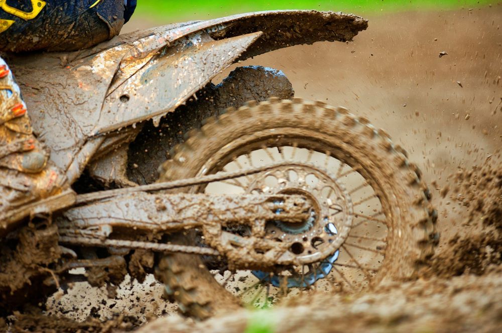 A Person is Riding a Dirt Bike Through the Mud — R & M Motorcycles in Katherine, NT