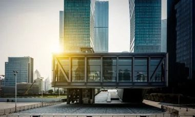 Skywalk connecting buildings in a city, with skyscrapers in background, bright sunlight.