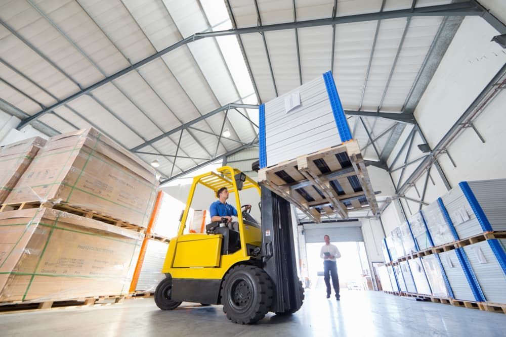 Forklift lifting a pallet of goods inside a warehouse.