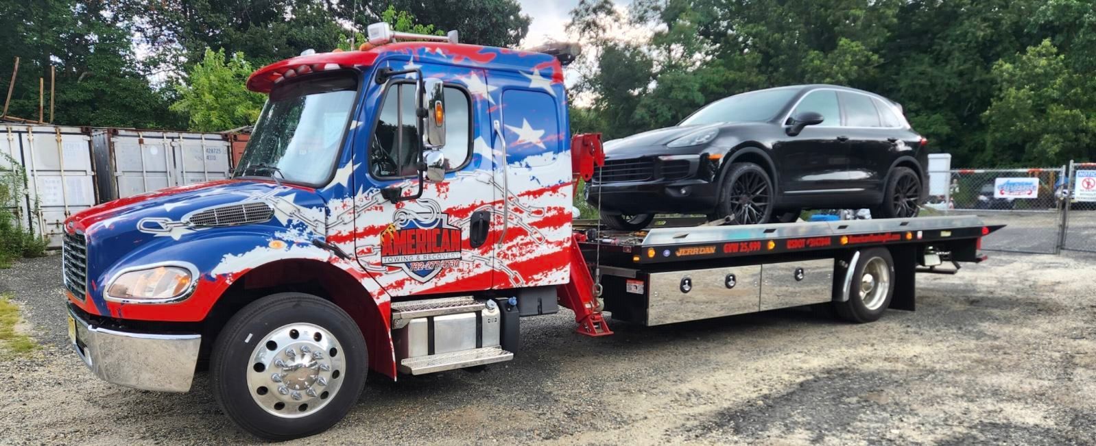 Tow truck with American flag paint job carrying a black car.