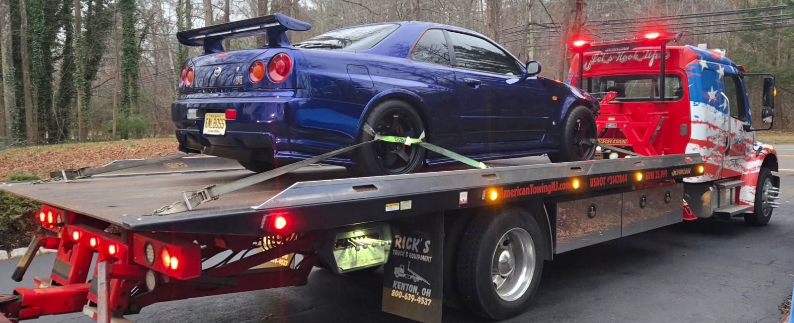 Blue sports car on a flatbed tow truck. The truck is red, white, and blue.