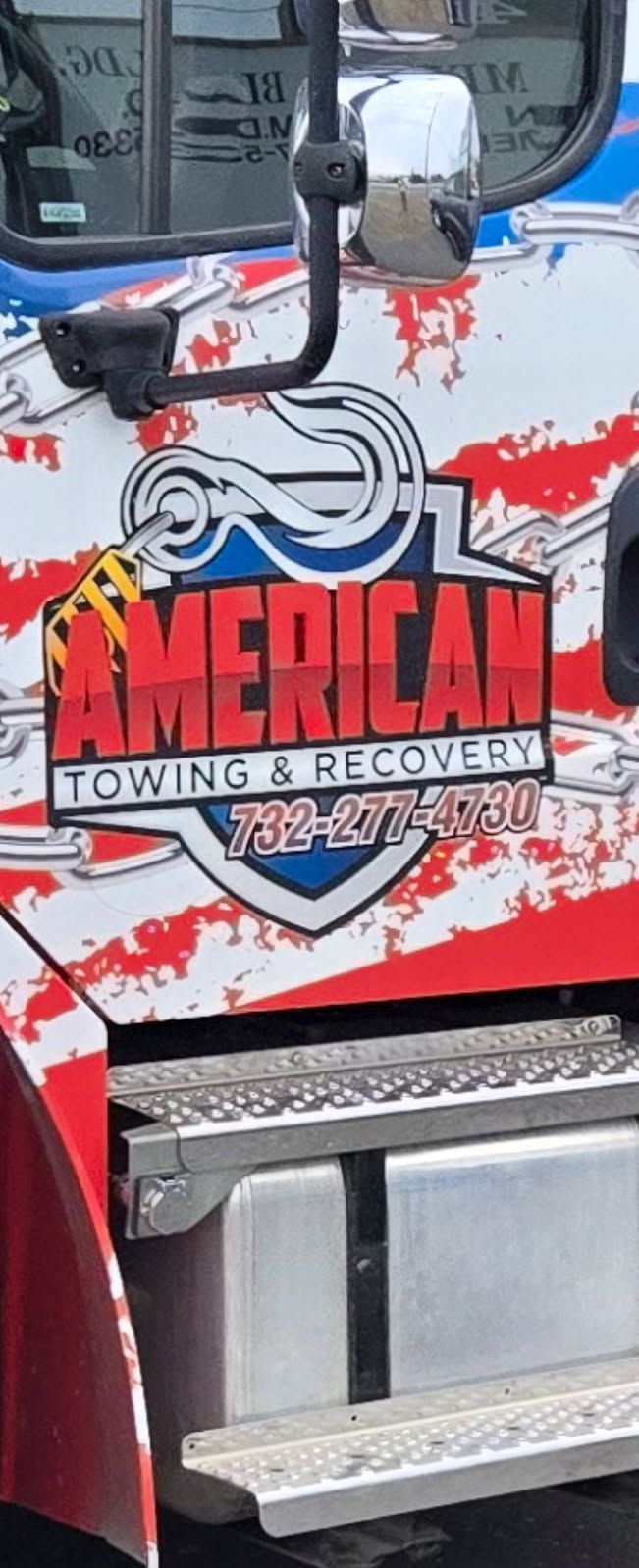 American Towing & Recovery logo on a truck with American flag paint.