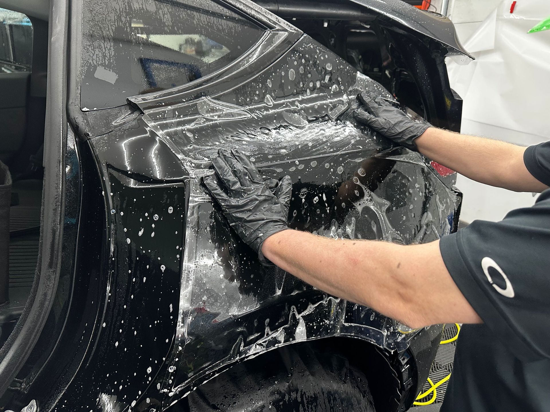 A man is wrapping a car with a piece of plastic.
