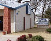 A white building with a blue roof and a sign in front of it.