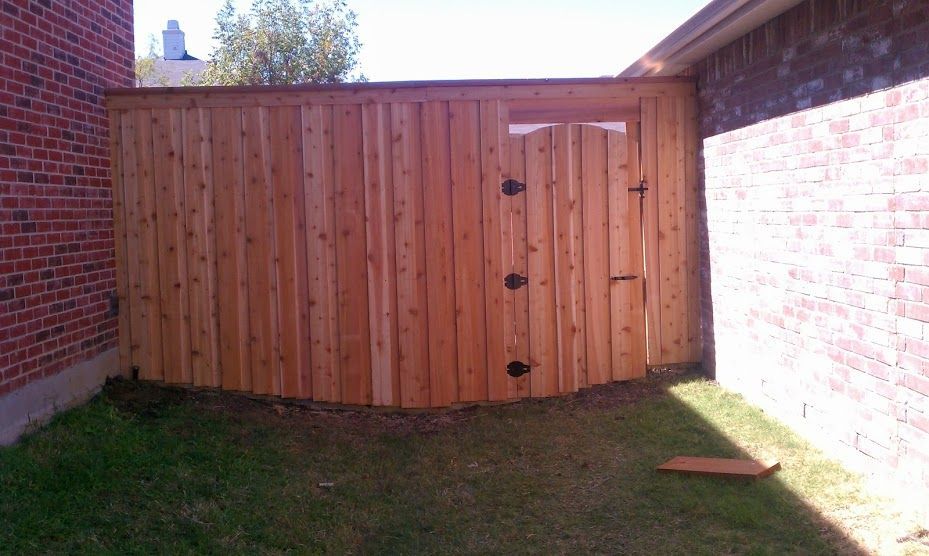 A wooden fence with a gate in the backyard of a house.