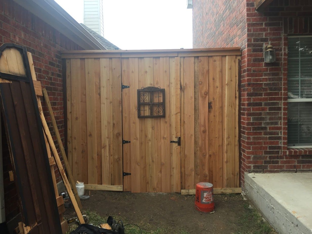 A wooden fence is sitting in front of a brick building.