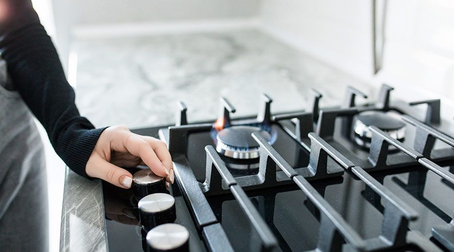 A person is turning a knob on a gas stove.