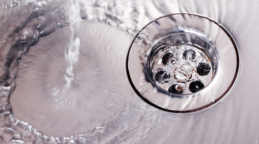 A close-up of a sink drain with water running down it.