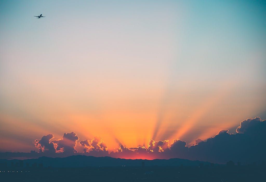 Plane flying over mountains during sunset. Photo by Jakob Owens on Unsplash