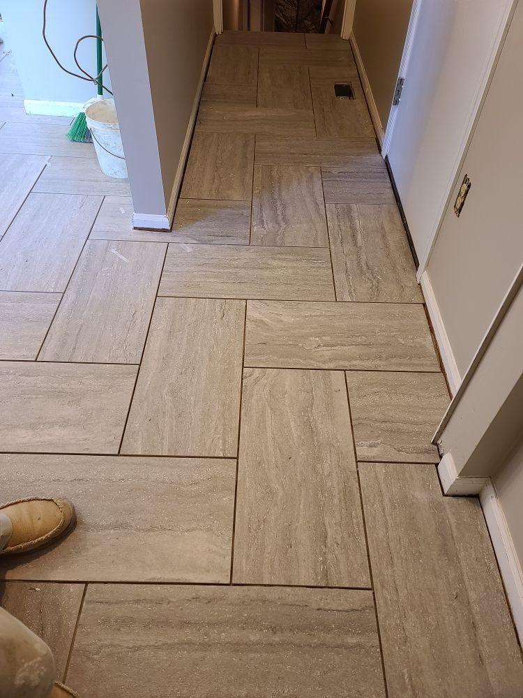 A person is standing on a tiled floor in a hallway.