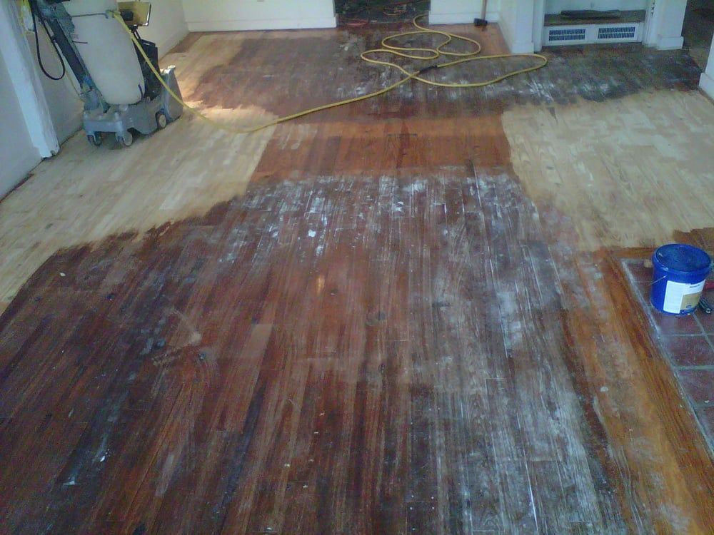 A wooden floor is being sanded with a machine.