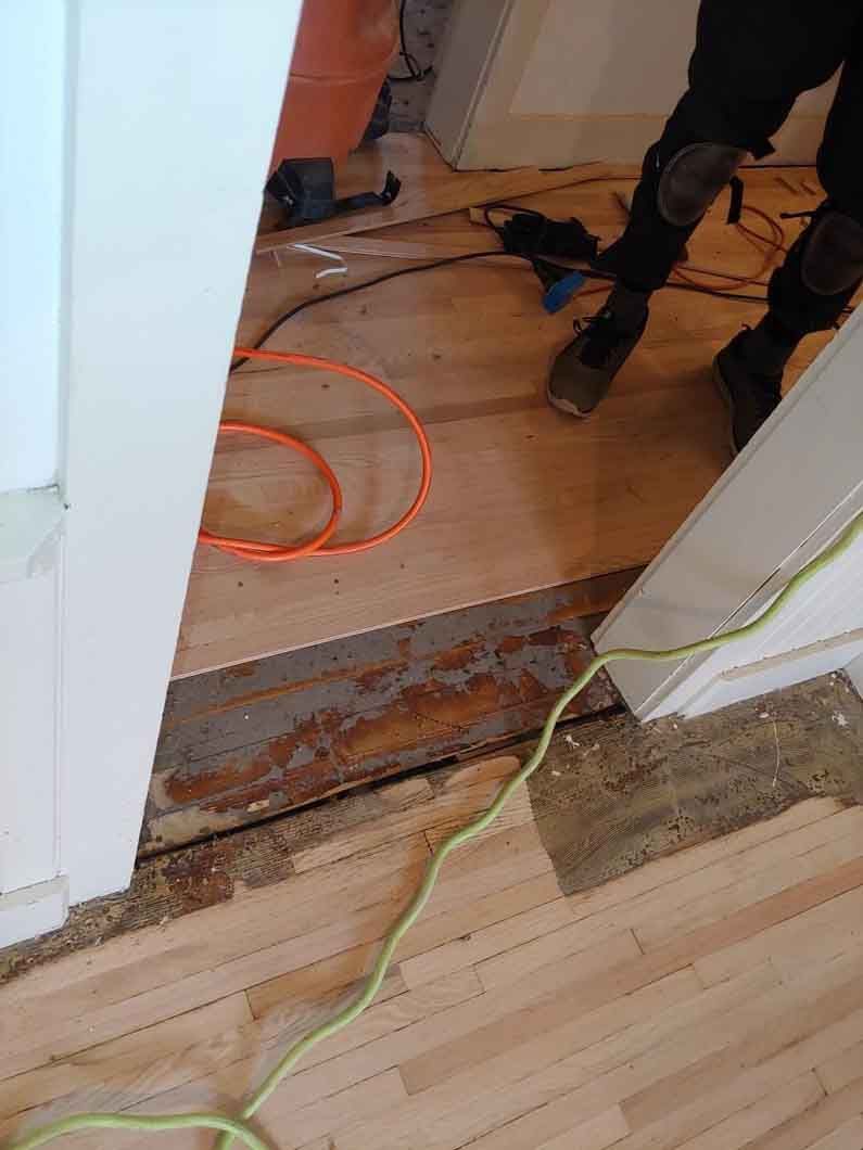 A person is working on a wooden floor in a room.