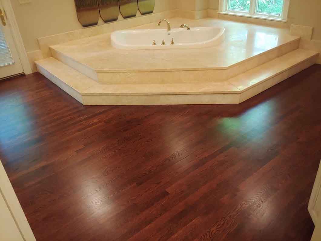 A bathtub in a bathroom with a wooden floor