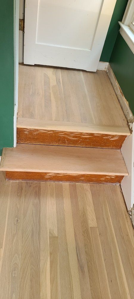 A pair of wooden stairs leading up to a door in a room.