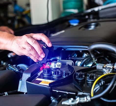 A person is working on the battery of a car.
