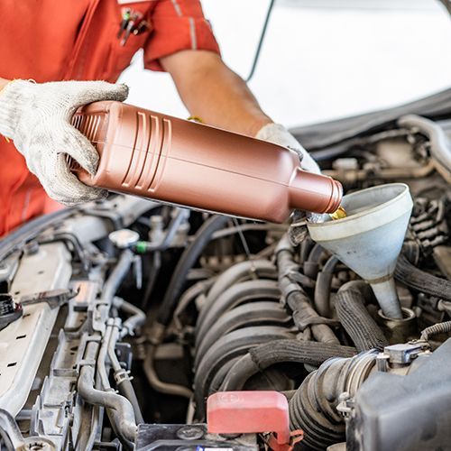 A man is pouring oil into a car engine.