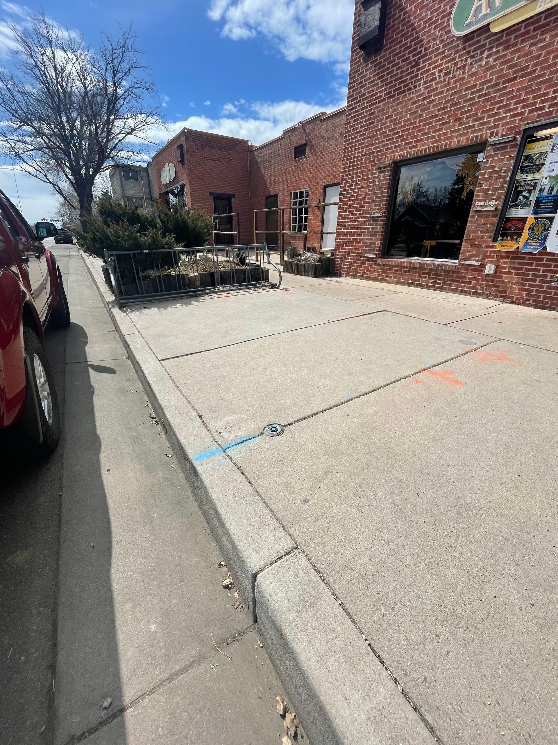 A person uses a textured stamp and hand tool to imprint a decorative pattern onto wet brown concrete pavers.