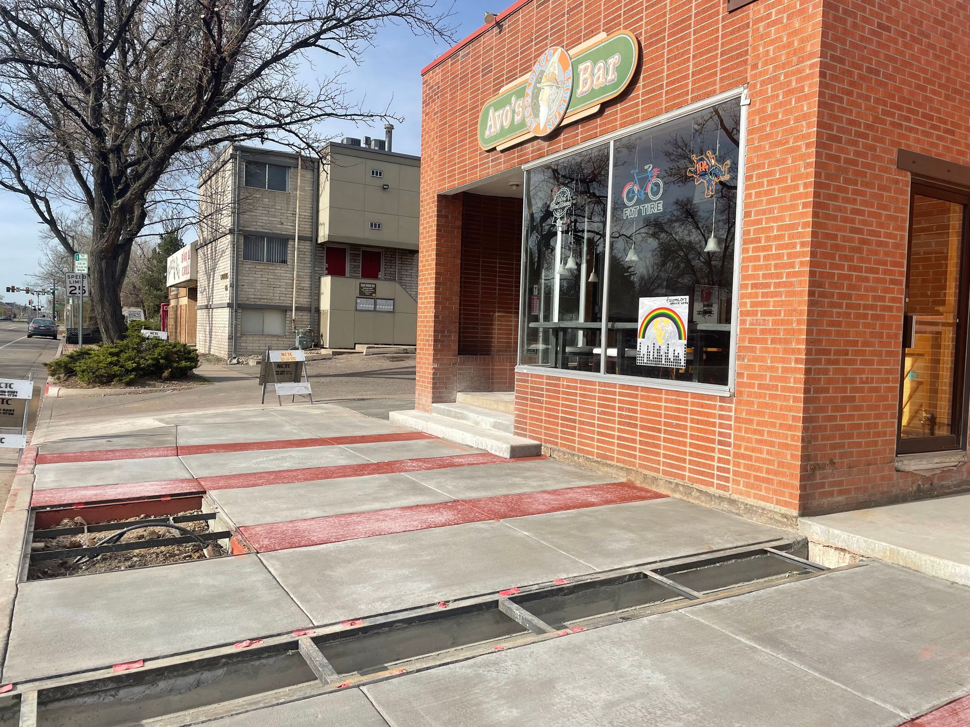 Construction workers pour wet concrete onto a metal-gridded floor inside a building structure.