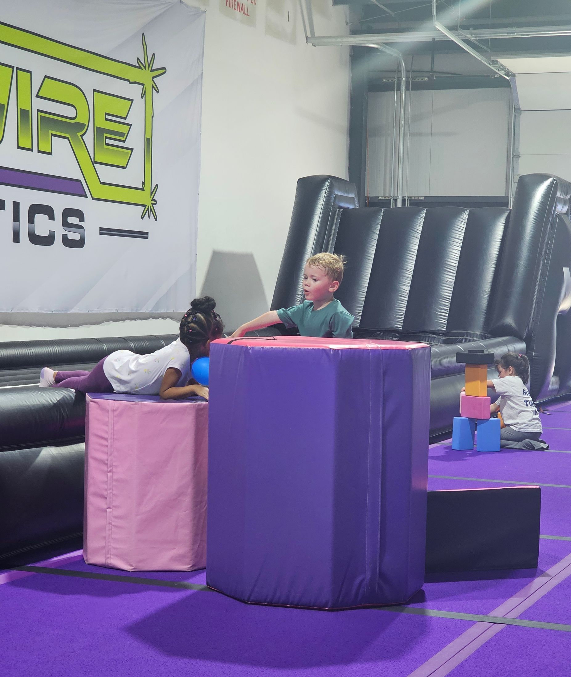 Children are playing in a gym with a sign that says fire tics