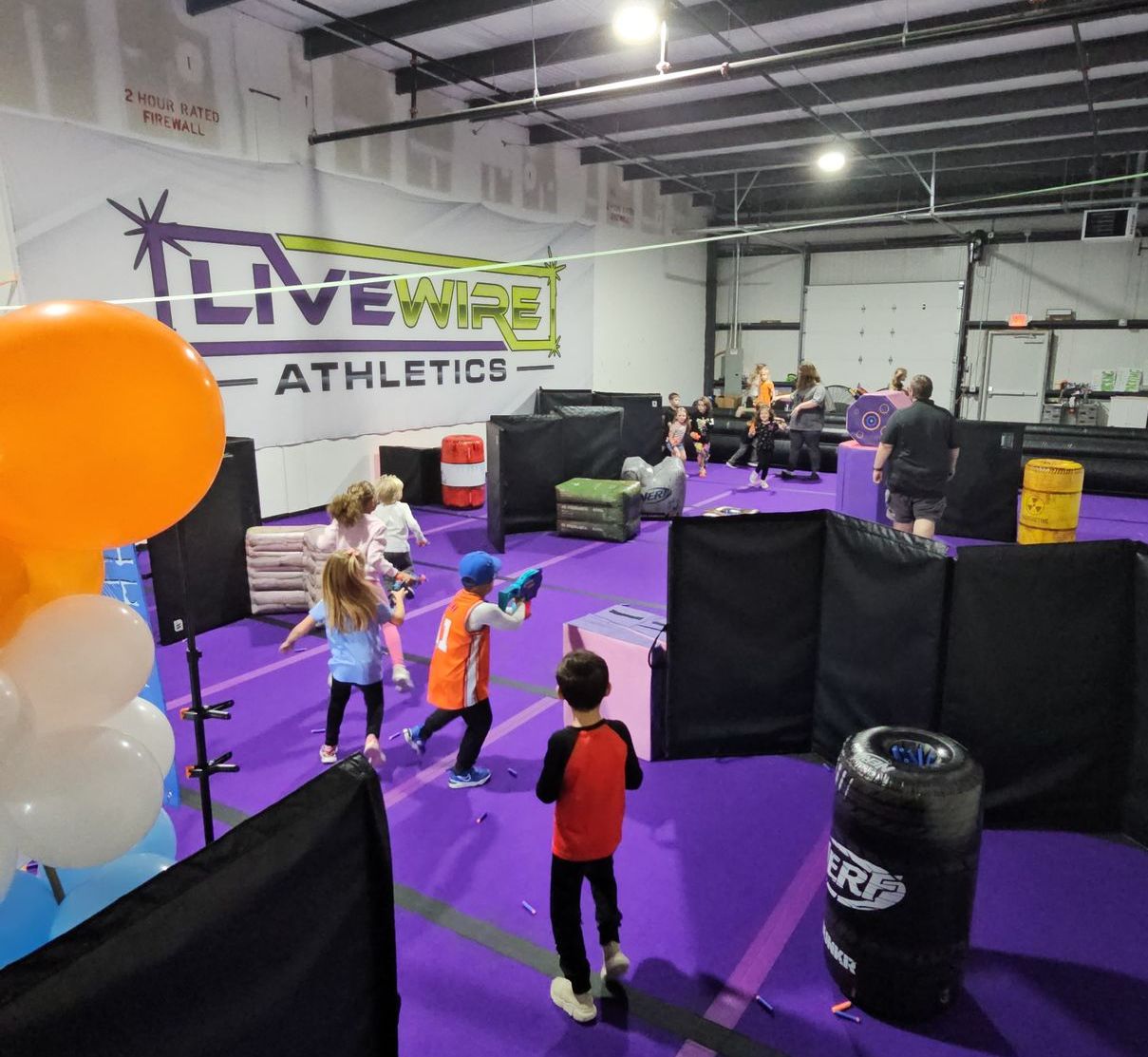 A group of children are playing a game of paintball at livewire athletics