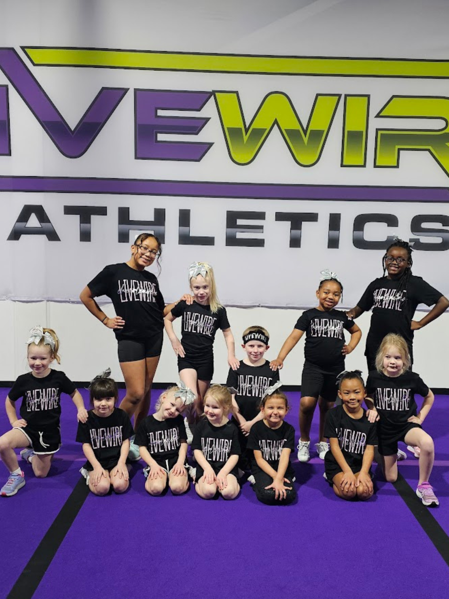 A group of young girls are posing for a picture in front of a sign that says athletics