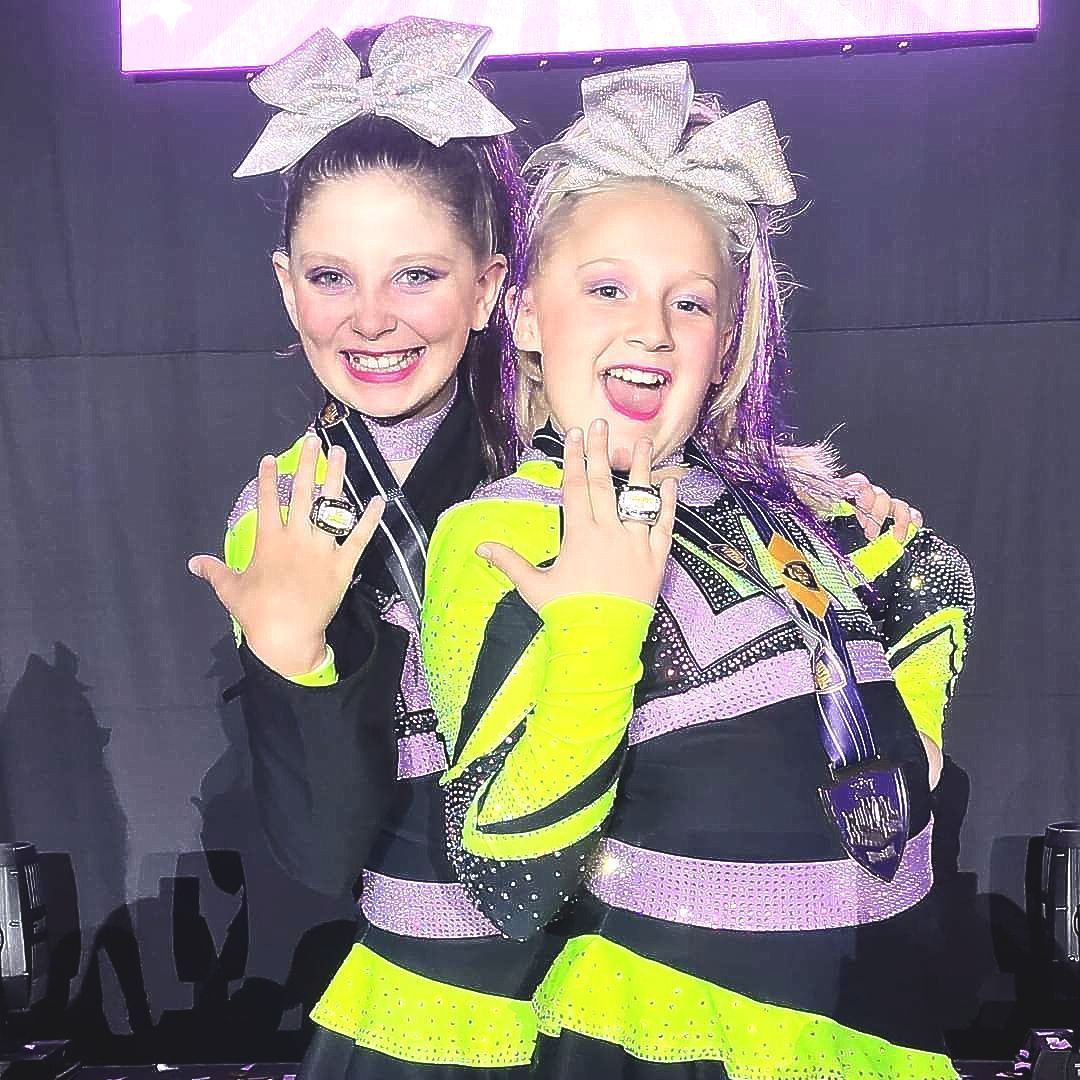 Two cheerleaders are posing for a picture together.