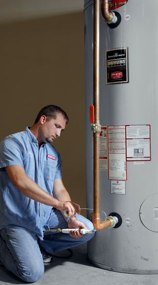 Kent Plumbing — Man Installing Pipe on Boiler  in Austin, TX