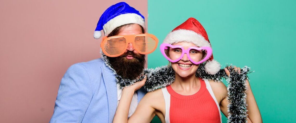 Couple with Christmas hats, costume glasses and christmas decorations