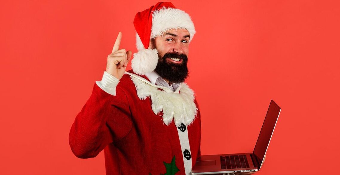 Man dressed as Santa holding a laptop
