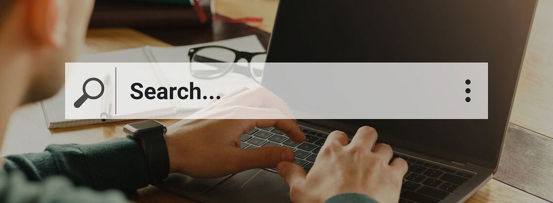 Representation of search box over a photo of someone typing on a laptop