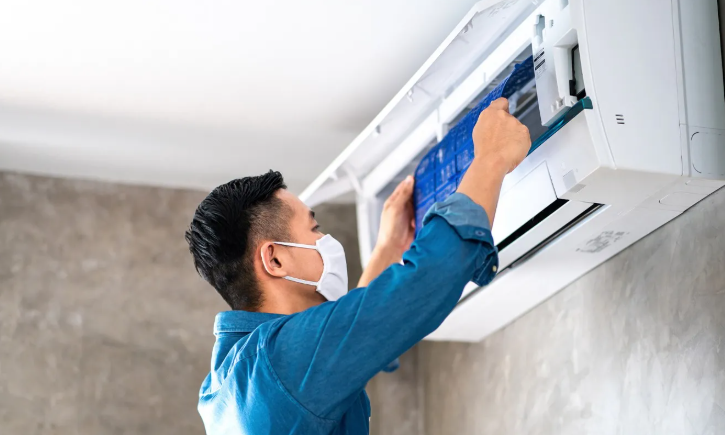 A man wearing a mask is cleaning an air conditioner.