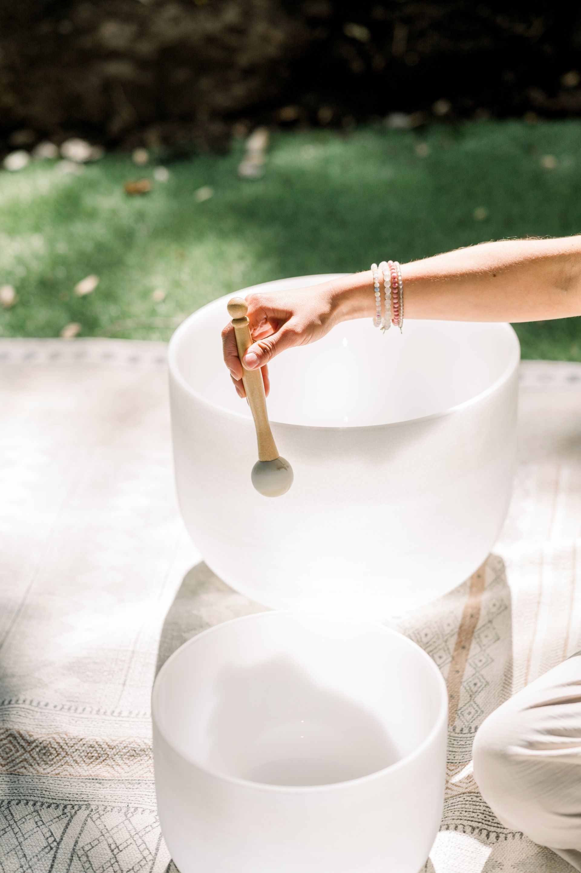 A person is playing a sound bowl with a wooden stick — Marie McAneney In Walkervale, QLD