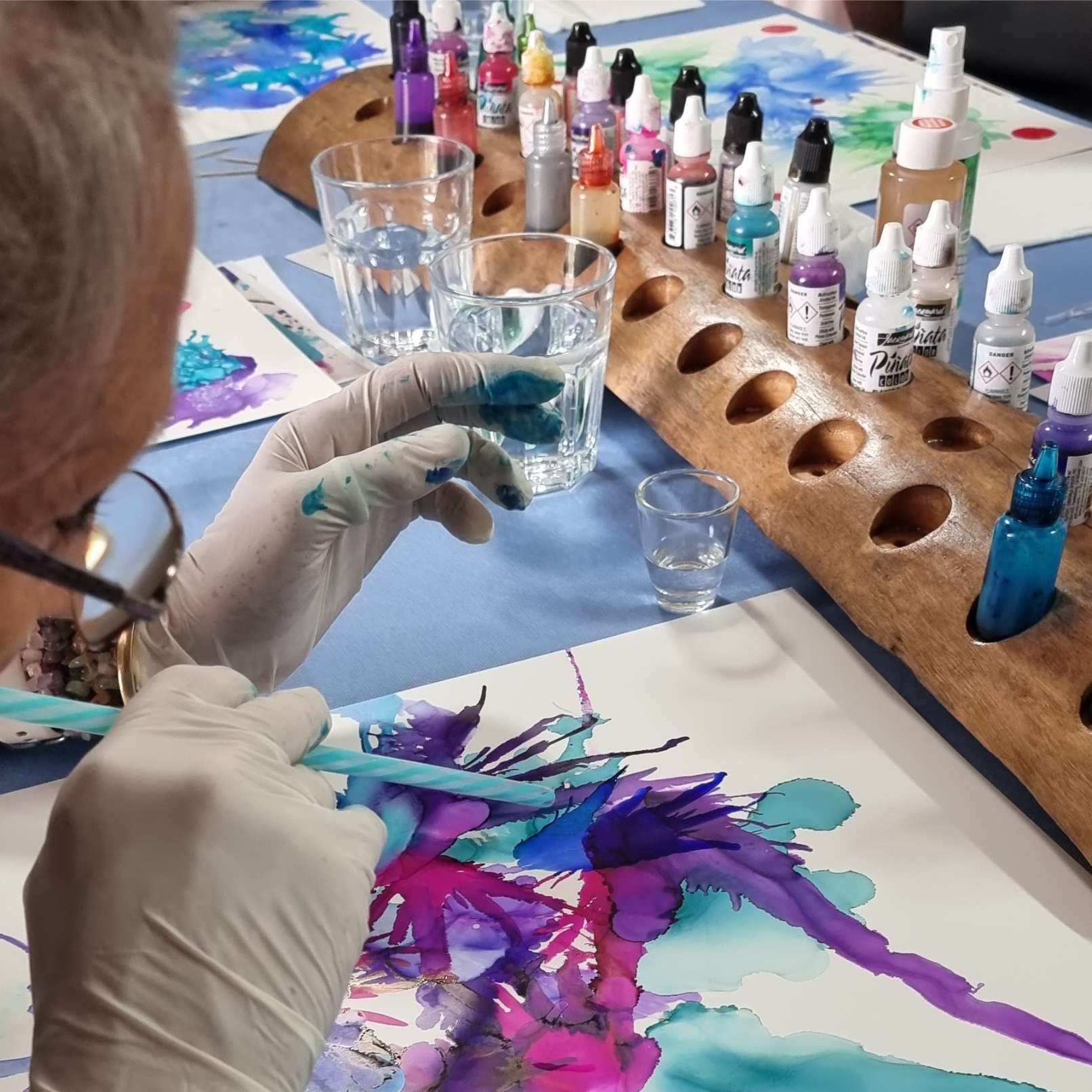 A woman is painting a picture with purple and blue paint — Marie McAneney In Walkervale, QLD