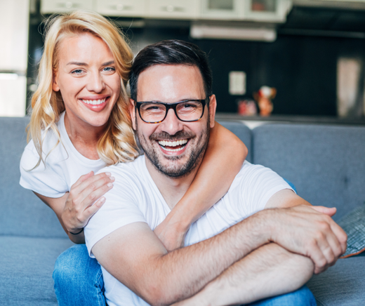 Smiling couple embracing on a blue couch in a home setting.