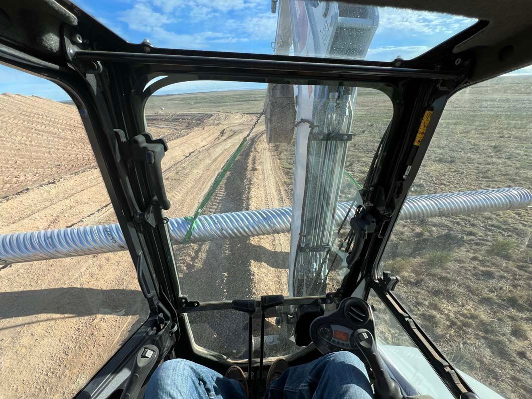A man is driving an excavator in a field.