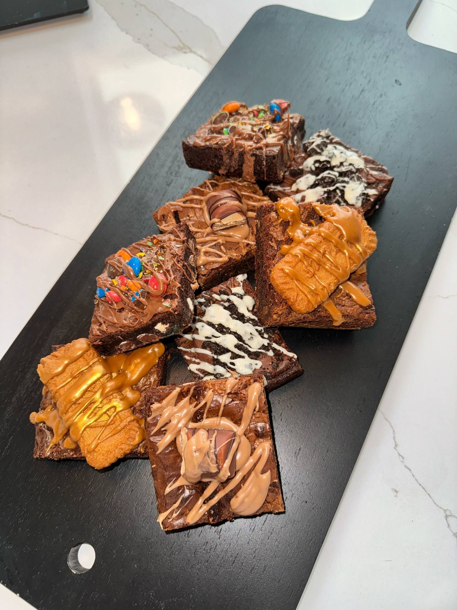 A black cutting board topped with a variety of brownies