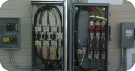 Open electrical panel with black, white, and red wires, circuit breakers, and other components, mounted on a wall.