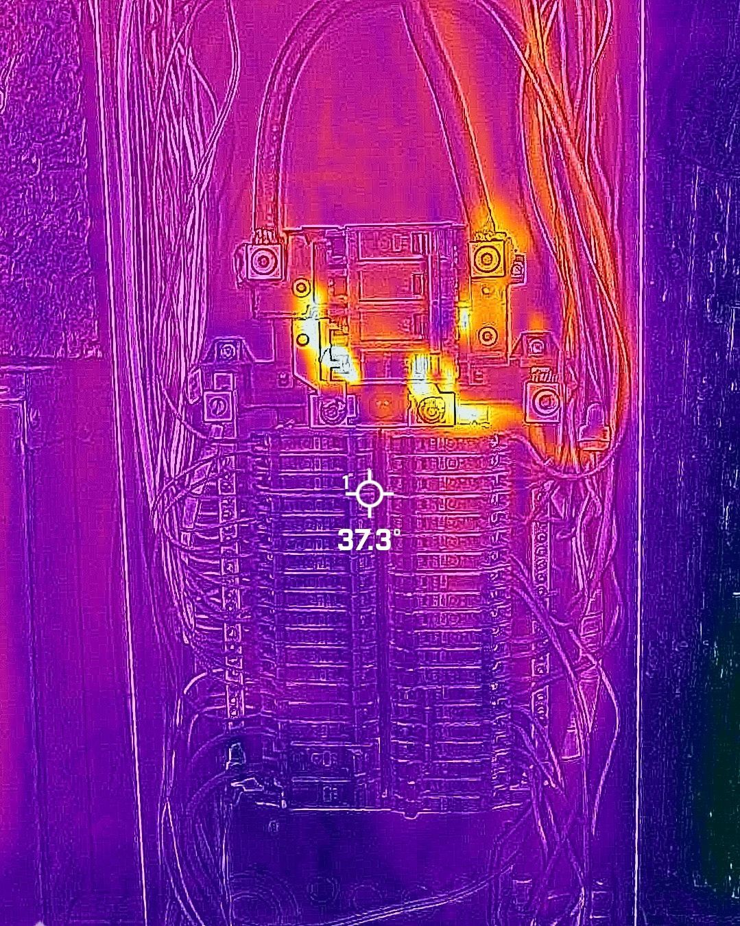 Thermal image of an electrical panel, showing areas of high heat in orange and yellow, indicating potential electrical issues.