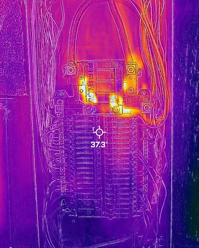 Thermal image of an electrical panel, showing areas of high heat in orange and yellow.