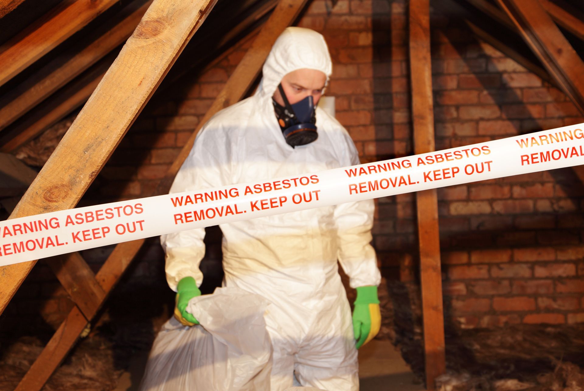 A man in a protective suit is holding a bag of asbestos.