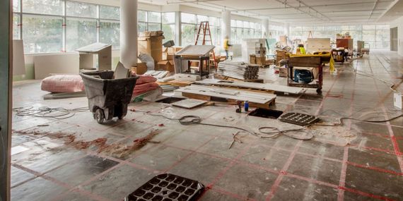A large room is being remodeled with a lot of trash on the floor.