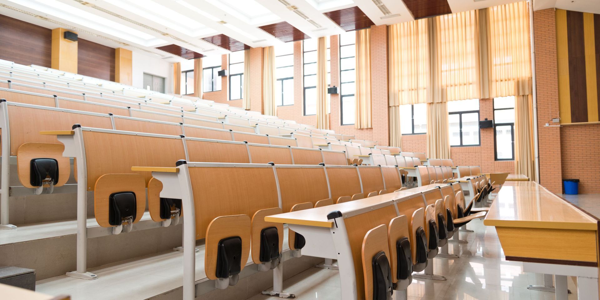 An empty lecture hall with rows of desks and chairs.