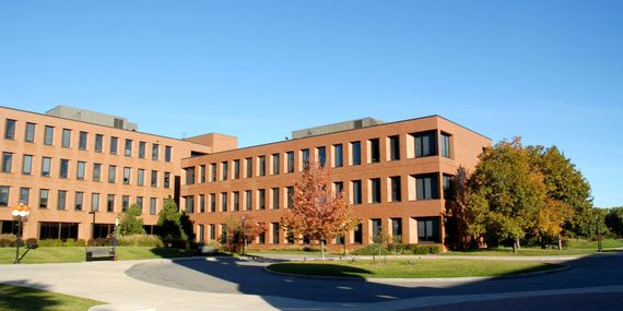 A large brick building with a lot of windows and trees in front of it