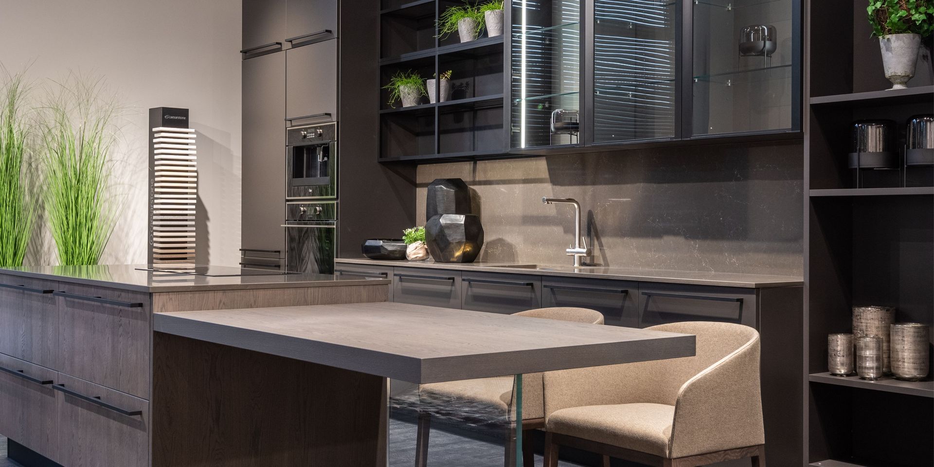 A kitchen with a large island , chairs , a sink and a refrigerator.