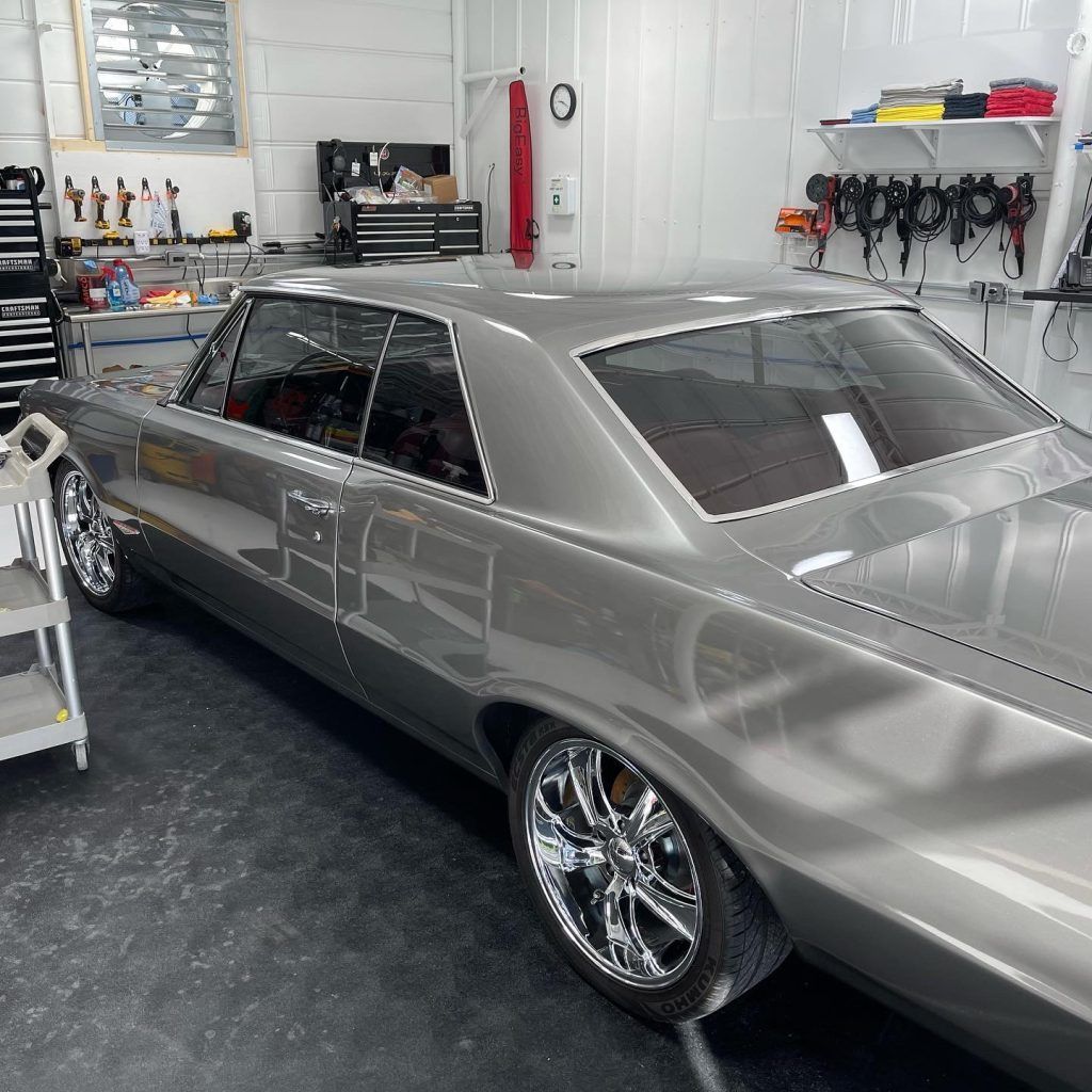 A silver car with chrome wheels is parked in a garage