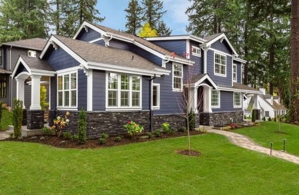 A large blue and white house with a lush green lawn in front of it.