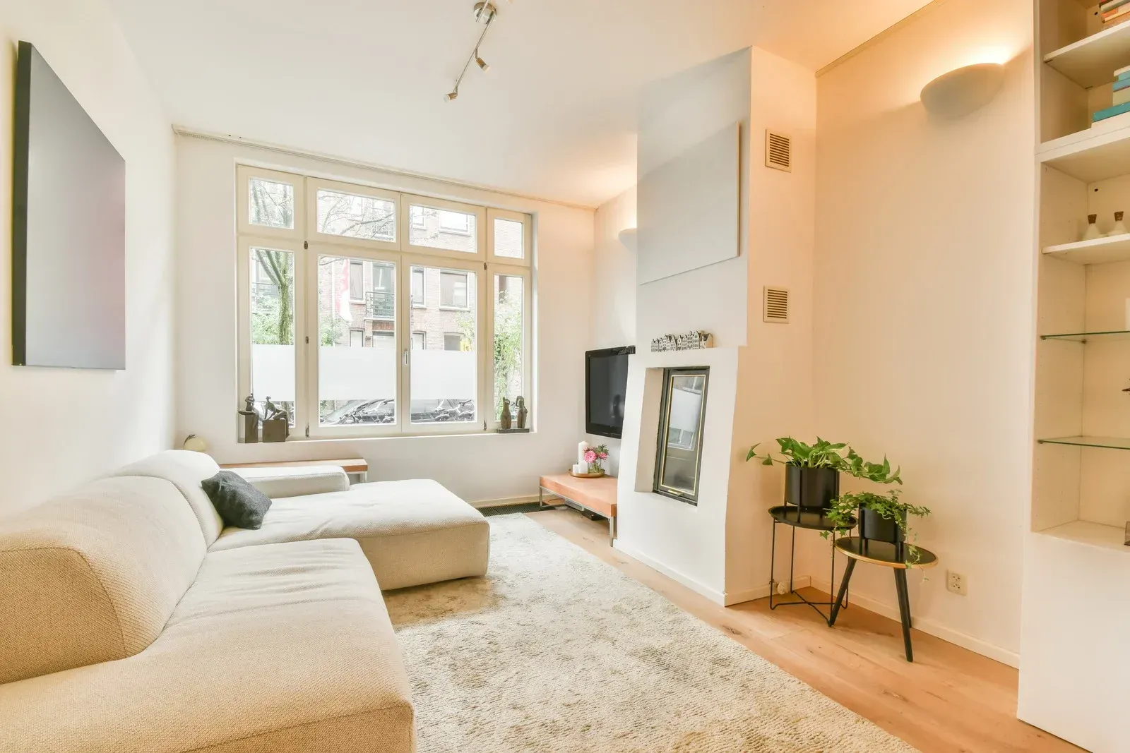 Living room with white sectional sofa, large window, fireplace, and shaggy rug.